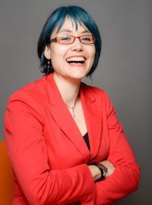 Jaigris Hodson in a red blazer posing and smiling to camera